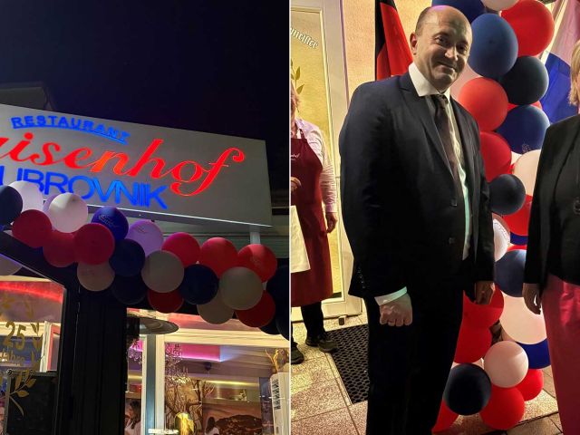 Restaurant storefront decorated with red, white, and blue balloons and a sign in cursive text above the entrance (nighttime storefront shot).