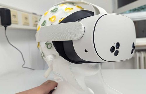 White VR headset strapped to a mannequin head wearing a patterned surgical cap in a medical setting.